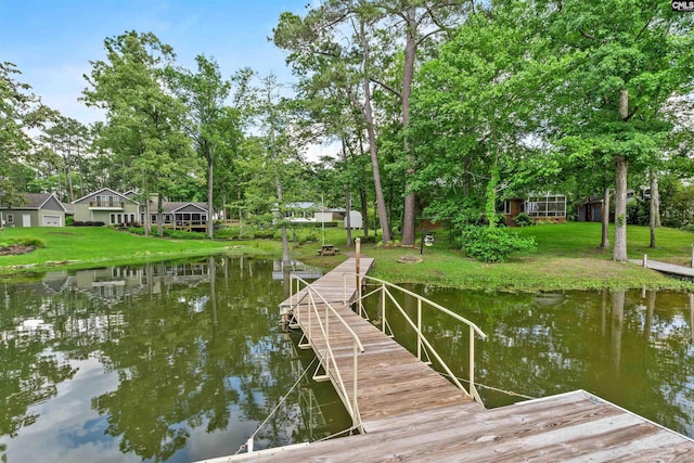 dock area with a water view, view of scattered trees, and a lawn
