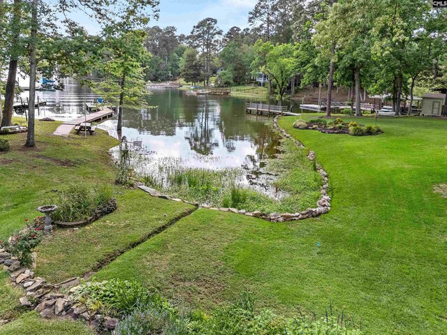 view of grassy yard featuring a water view and a dock