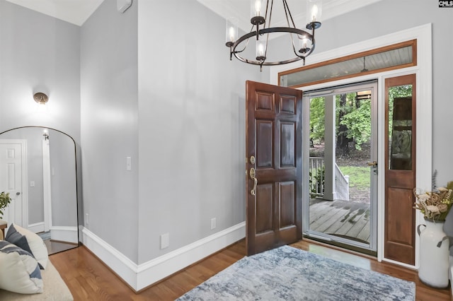 entryway featuring a chandelier, wood finished floors, and baseboards
