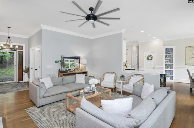 living area with ornamental molding, a ceiling fan, a chandelier, plenty of natural light, and dark wood-style flooring