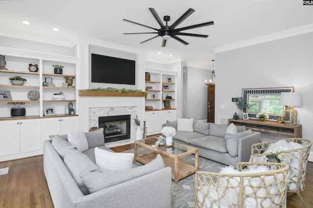 living room featuring crown molding, dark wood-type flooring, a ceiling fan, a high end fireplace, and recessed lighting
