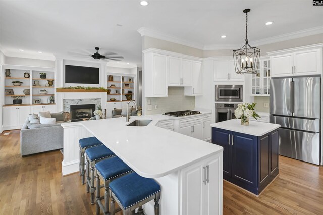 kitchen with stainless steel appliances, a sink, a ceiling fan, white cabinetry, and ornamental molding
