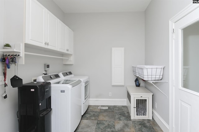 washroom with cabinet space, washer and dryer, baseboards, and stone finish floors