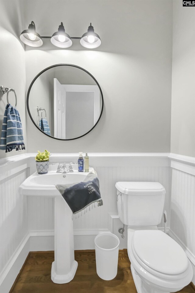 bathroom featuring wood finished floors, wainscoting, and toilet