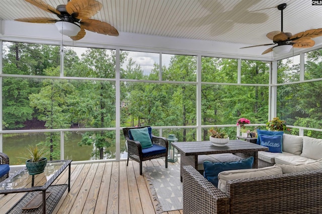 sunroom / solarium featuring ceiling fan, outdoor lounge area, and view of wooded area