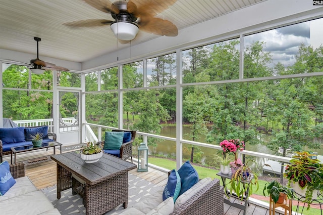 sunroom with an outdoor hangout area, ceiling fan, a water view, and view of scattered trees