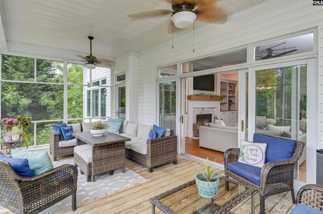 sunroom / solarium featuring ceiling fan, an outdoor living space with a fireplace, and healthy amount of natural light