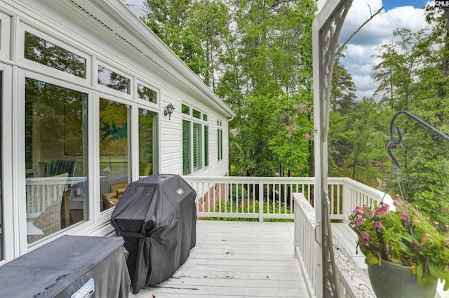 wooden deck featuring grilling area and view of wooded area