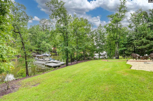 view of green lawn with a dock and a water view