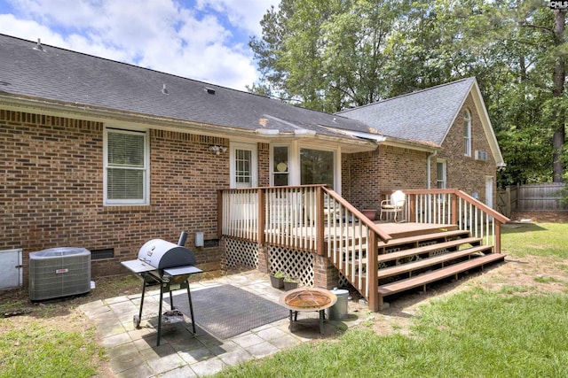 rear view of house with a fire pit, a deck, brick siding, roof with shingles, and a patio area