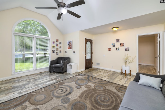 living room featuring wood finished floors, vaulted ceiling, a ceiling fan, and baseboards