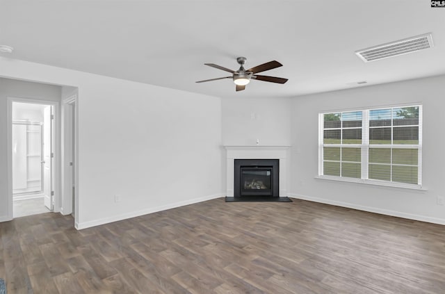 unfurnished living room featuring a ceiling fan, dark wood finished floors, a fireplace with flush hearth, and baseboards