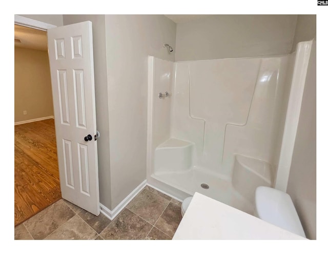 full bath with a shower, baseboards, and toilet