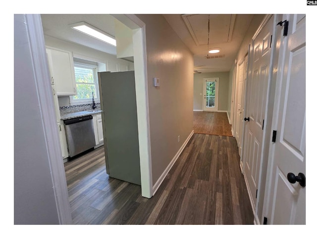 hallway featuring attic access, dark wood-style floors, baseboards, and a sink