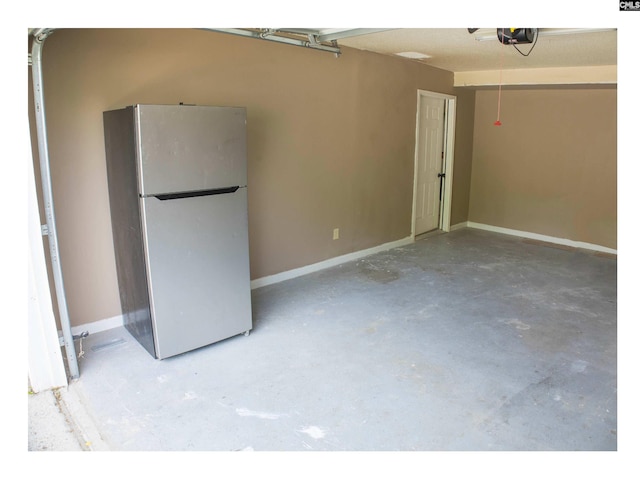garage featuring freestanding refrigerator, a garage door opener, and baseboards