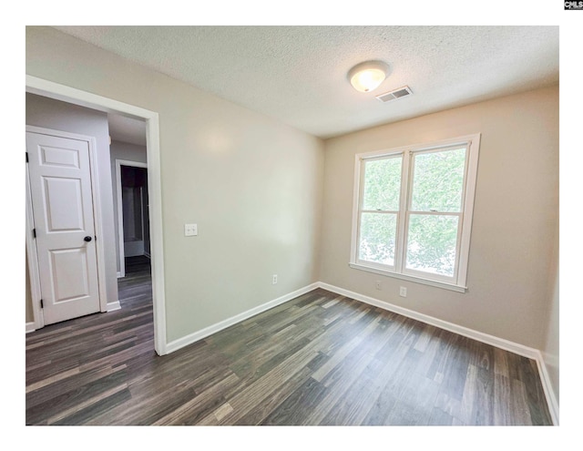 spare room featuring baseboards, dark wood-style flooring, and a textured ceiling
