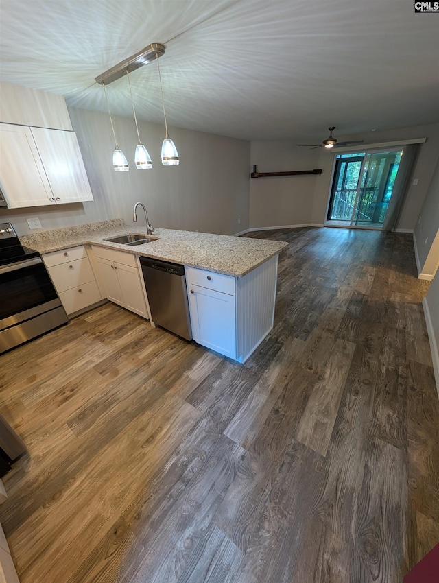 kitchen featuring appliances with stainless steel finishes, a sink, a ceiling fan, dark wood-style floors, and a peninsula