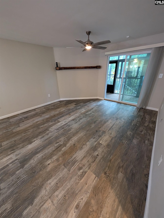 spare room with dark wood-style flooring, a ceiling fan, and baseboards