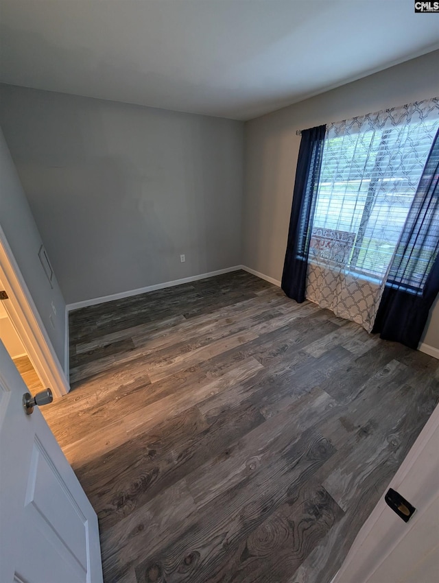 empty room with dark wood-style floors and baseboards