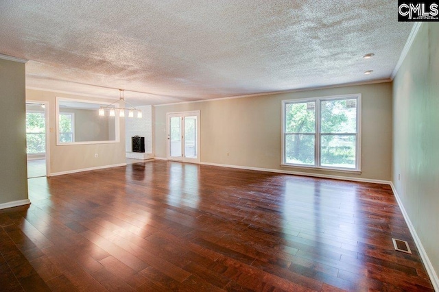 7905 Castleton Ln, Columbia, SC 29223 - unfurnished living room with ornamental molding, a textured ceiling, plenty of natural light, a chandelier, and dark wood-style flooring