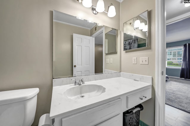 bathroom featuring vanity, toilet, ornamental molding, and wood finished floors