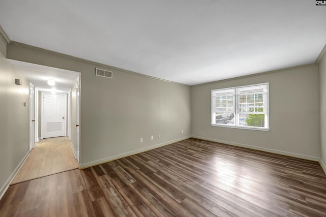 spare room featuring wood finished floors, ornamental molding, and baseboards