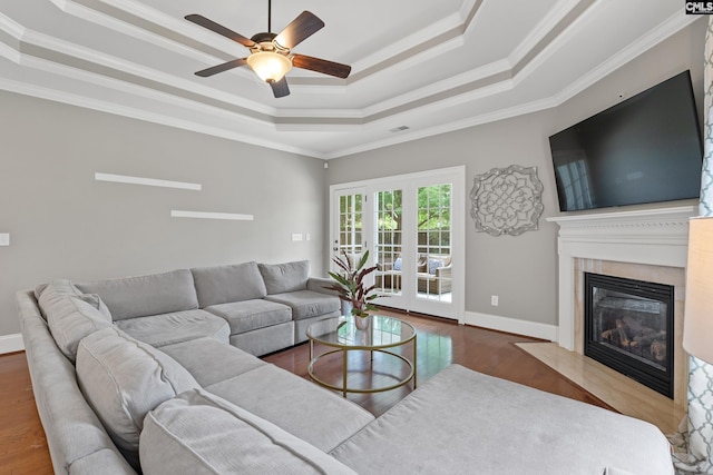 living room featuring a tray ceiling, a high end fireplace, crown molding, ceiling fan, and wood finished floors