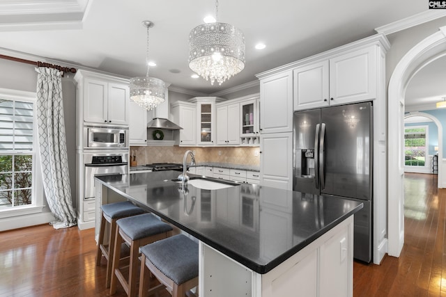 kitchen with stainless steel appliances, a sink, ornamental molding, a chandelier, and dark wood-style floors