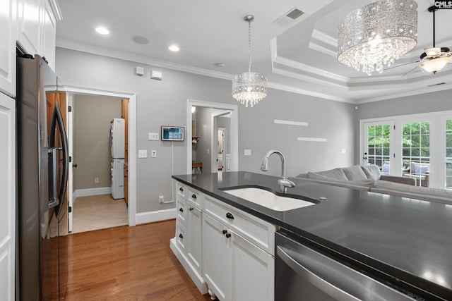 kitchen featuring a sink, appliances with stainless steel finishes, a chandelier, dark countertops, and crown molding