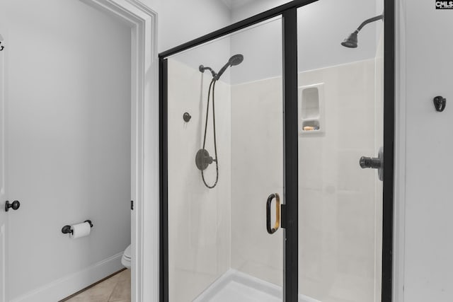 bathroom featuring a shower stall, baseboards, and toilet