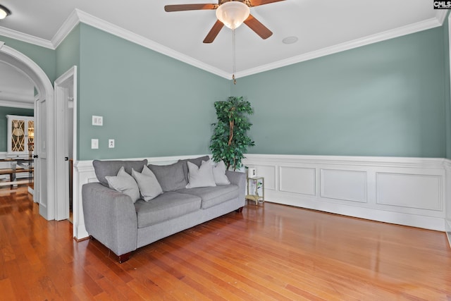 living area with a ceiling fan, crown molding, arched walkways, and wood finished floors