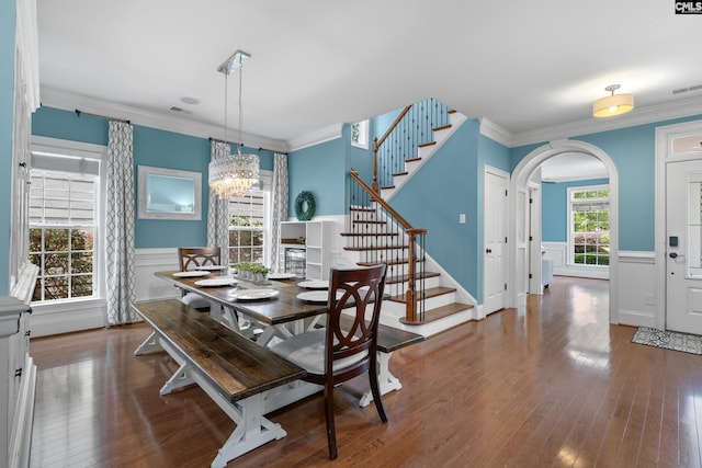 dining space with ornamental molding, arched walkways, stairway, a wainscoted wall, and hardwood / wood-style floors