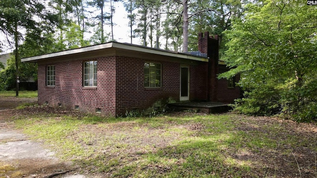 view of home's exterior featuring crawl space, a chimney, and brick siding