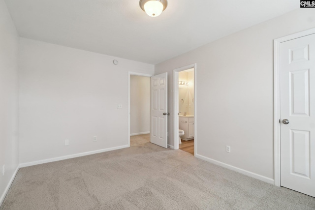 unfurnished bedroom featuring light colored carpet, baseboards, and ensuite bathroom