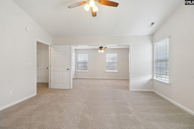 spare room with ceiling fan, plenty of natural light, and light carpet