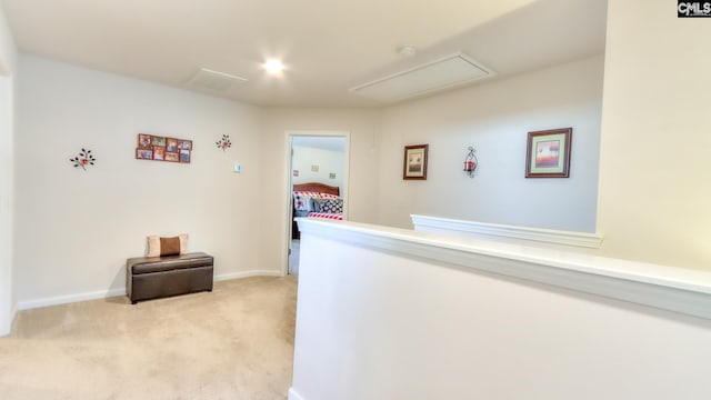 hall featuring attic access, light colored carpet, and baseboards