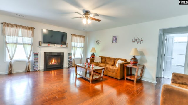 living room featuring healthy amount of natural light, ceiling fan, wood finished floors, and a fireplace with flush hearth