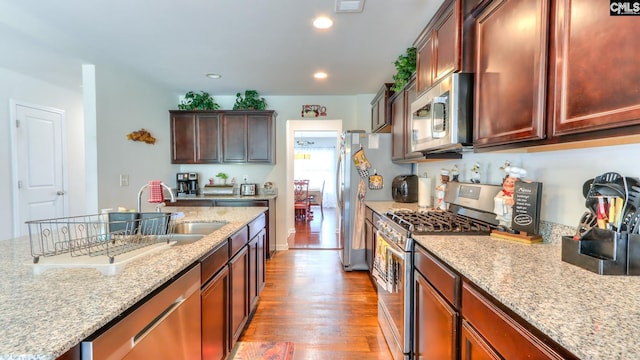 kitchen featuring stainless steel appliances, light wood-style floors, light stone counters, recessed lighting, and a sink