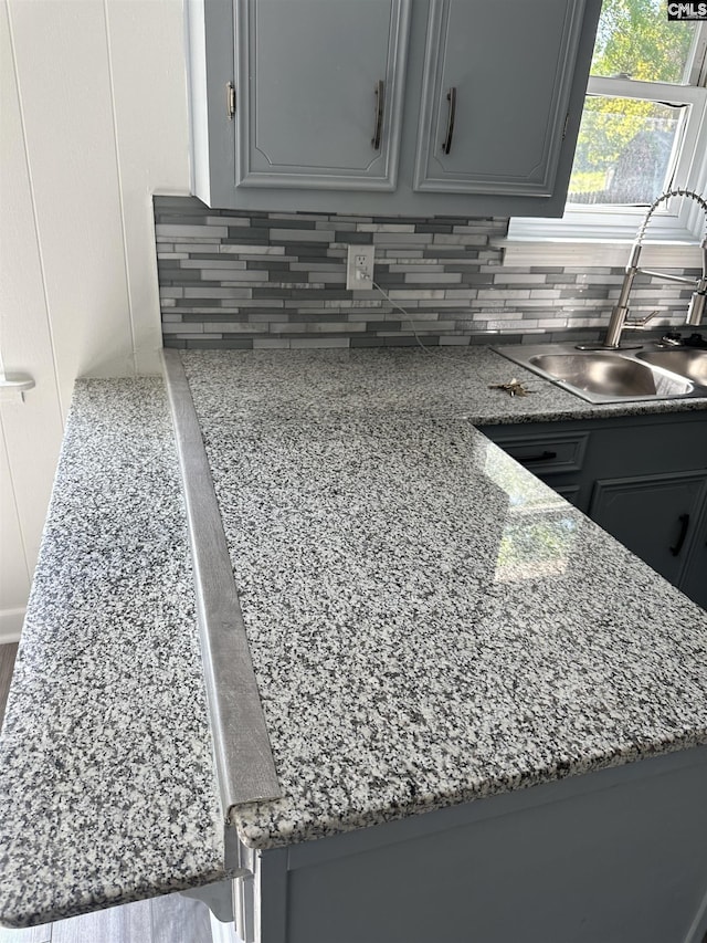 kitchen featuring gray cabinetry, tasteful backsplash, and a sink