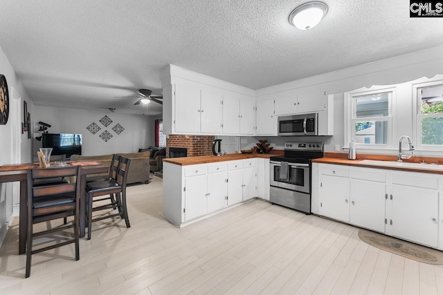 4306 Windemere Ave, Columbia, SC 29203 - kitchen featuring appliances with stainless steel finishes, a sink, butcher block counters, open floor plan, and a textured ceiling