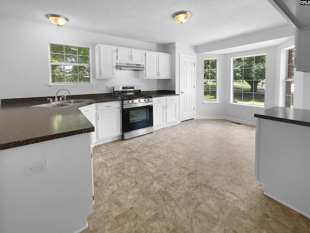 kitchen featuring gas range, dark countertops, under cabinet range hood, white cabinetry, and light floors