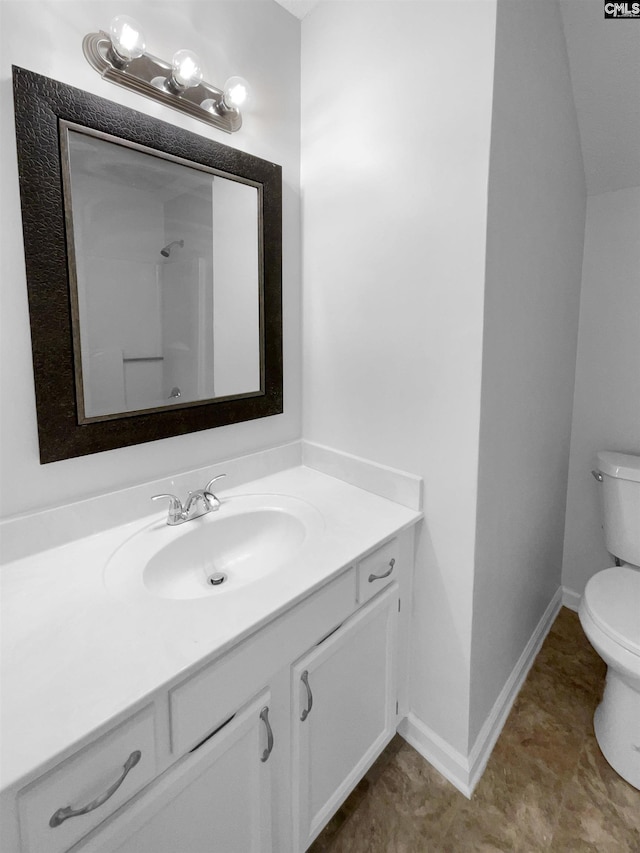 bathroom featuring toilet, vanity, baseboards, and a shower