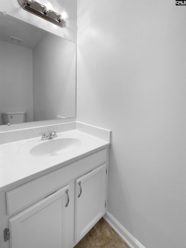 bathroom featuring vanity, toilet, and baseboards