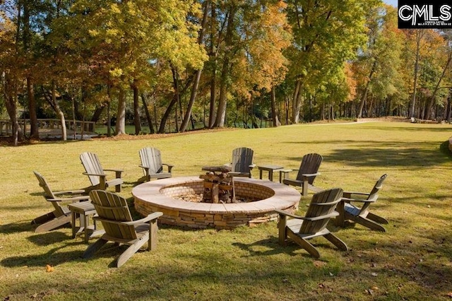 view of grassy yard with a fire pit and view of wooded area