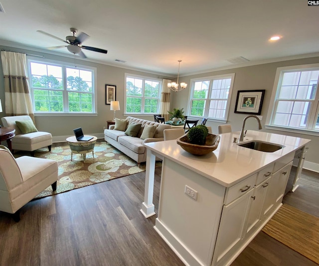 kitchen featuring a sink, open floor plan, white cabinets, baseboards, and crown molding