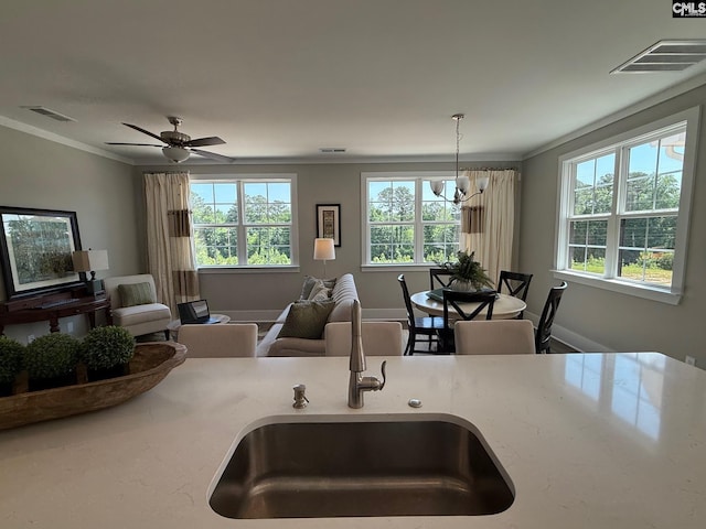 kitchen featuring a sink, crown molding, open floor plan, pendant lighting, and a ceiling fan