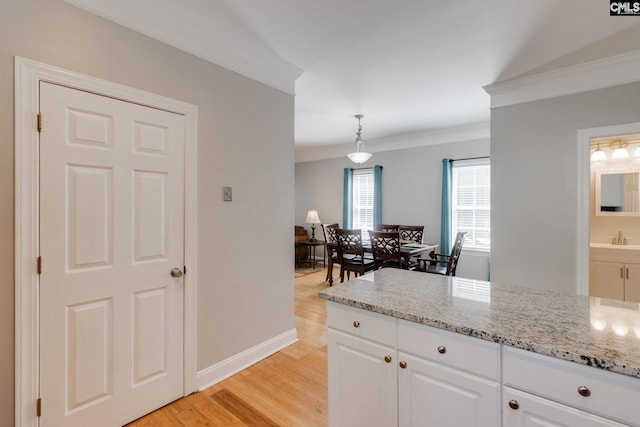 1029 Maxcy St, Columbia, SC 29201 - kitchen featuring ornamental molding, light wood-style flooring, light stone countertops, white cabinets, and pendant lighting