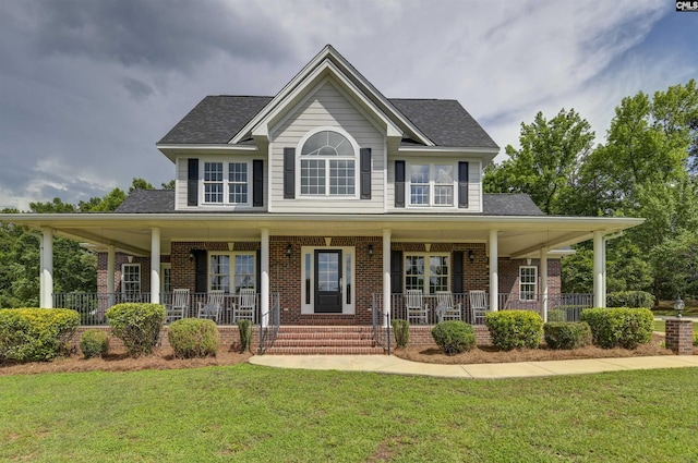 view of front of home with brick siding, covered porch, and a front lawn