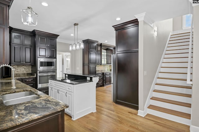 kitchen with stainless steel appliances, tasteful backsplash, a sink, recessed lighting, and light wood finished floors