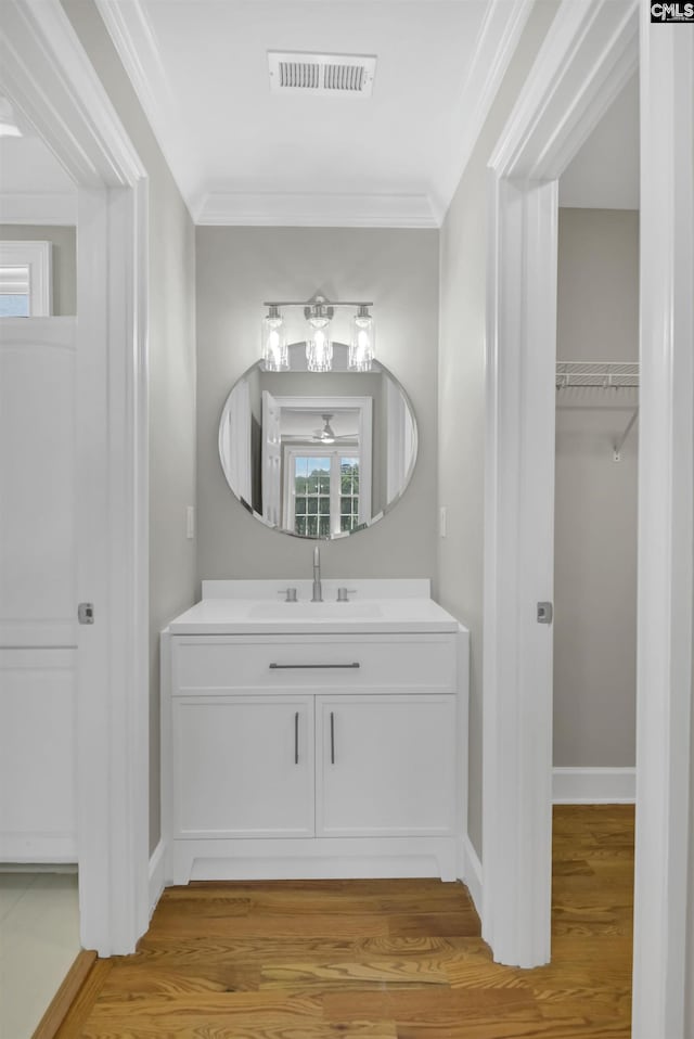 bathroom with wood finished floors, vanity, ornamental molding, and baseboards